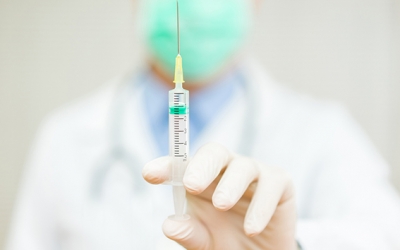 Doctor is holding an injection with needle with focus on injection