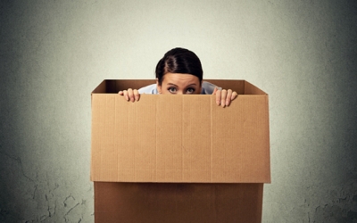 Young woman hiding in a carton box