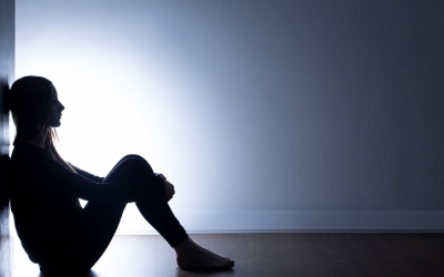 Teenager with depression sitting alone in dark room